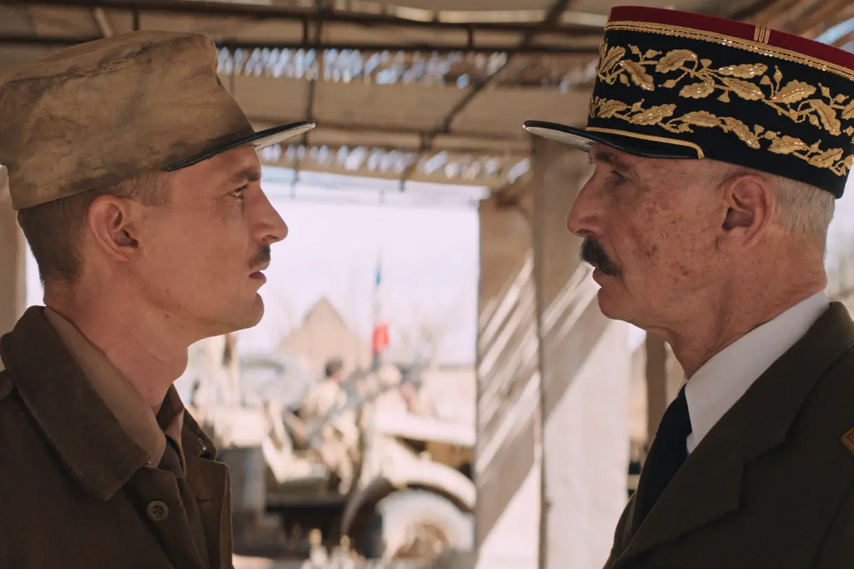 Deux hommes en uniforme militaire se font face sous une structure en bois.