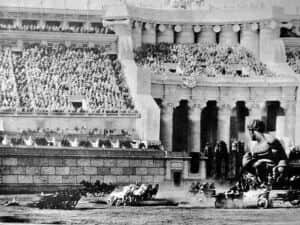 Un attelage traverse une arène romaine devant des gradins bondés de spectateurs.