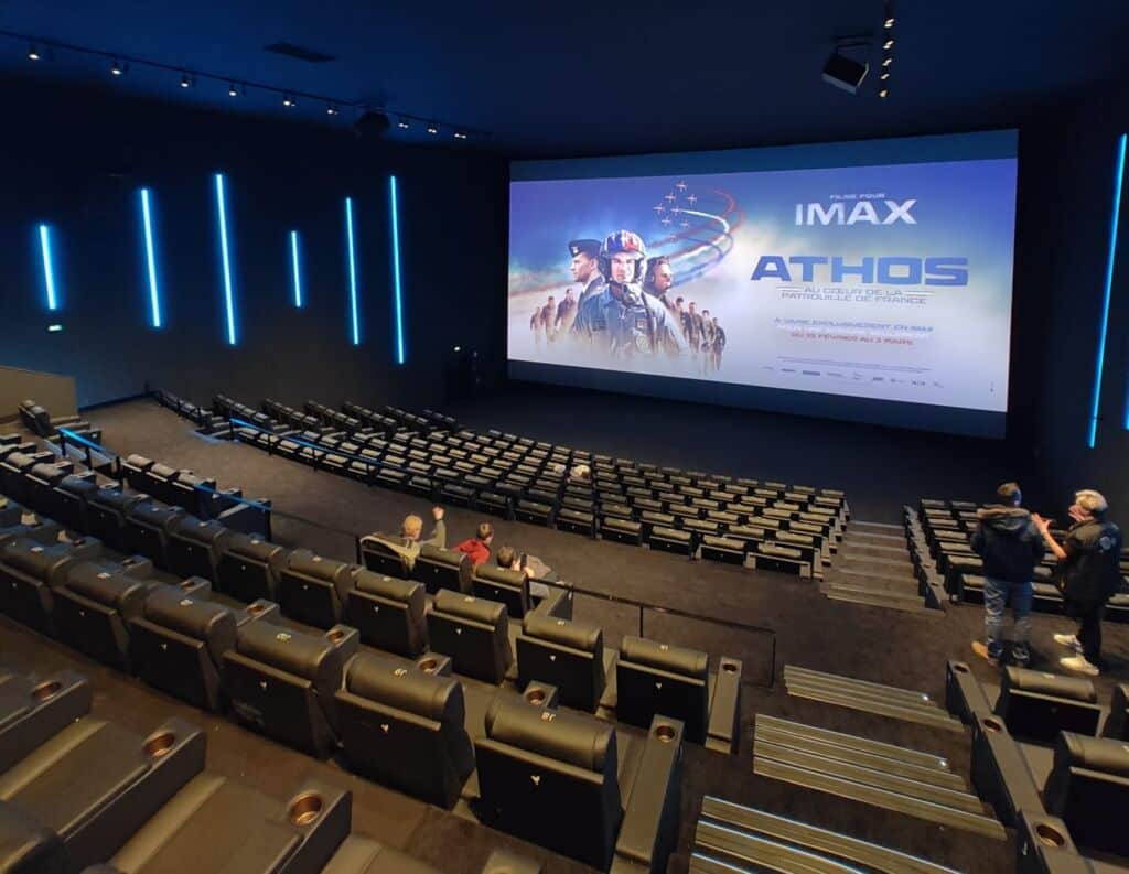 Affiche de « ATHOS » avec un groupe de personnages en uniforme projetée dans une salle de cinéma IMAX.