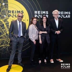 Quatre personnes posent devant un décor noir marqué « REIMS POLAR », avec un motif cartographique jaune.
