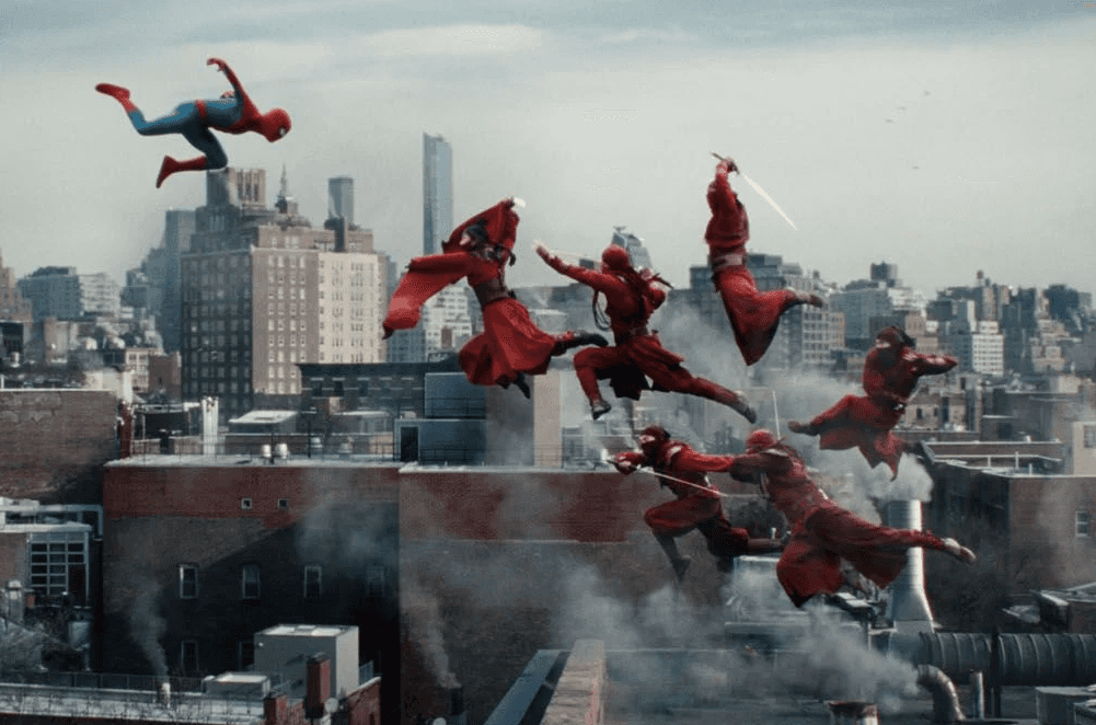 Un groupe de personnes en costumes rouges bondit et combat sur des toits, avec une personne en rouge et bleu dans les airs.