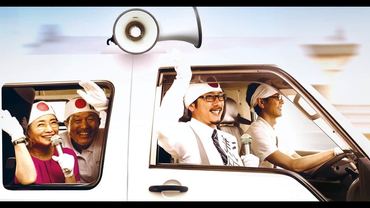 Un groupe de personnes en voiture, portant des couvre-chefs blancs et tenant des microphones, avec un mégaphone au-dessus.