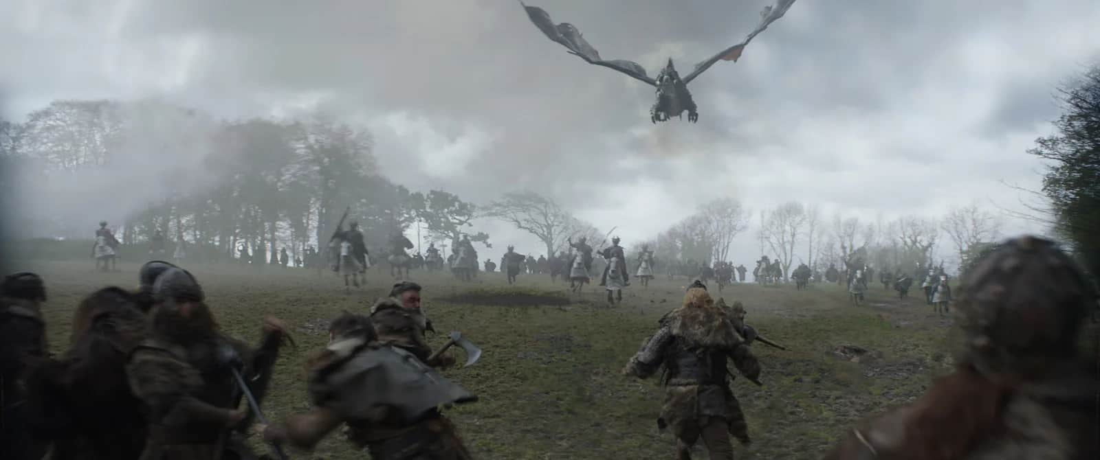 Un groupe de guerriers avance sur une colline brumeuse tandis qu’un dragon vole au-dessus d’eux.