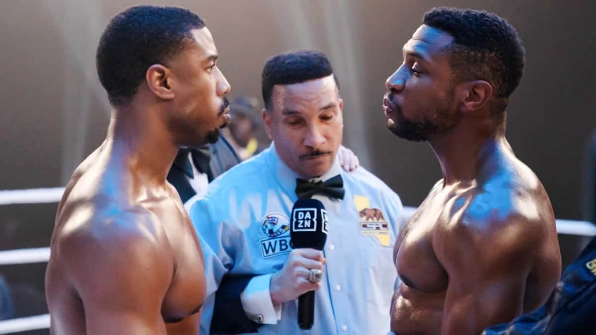 Deux boxeurs se font face dans un ring, tandis qu’un arbitre tient un micro DAZN entre eux.