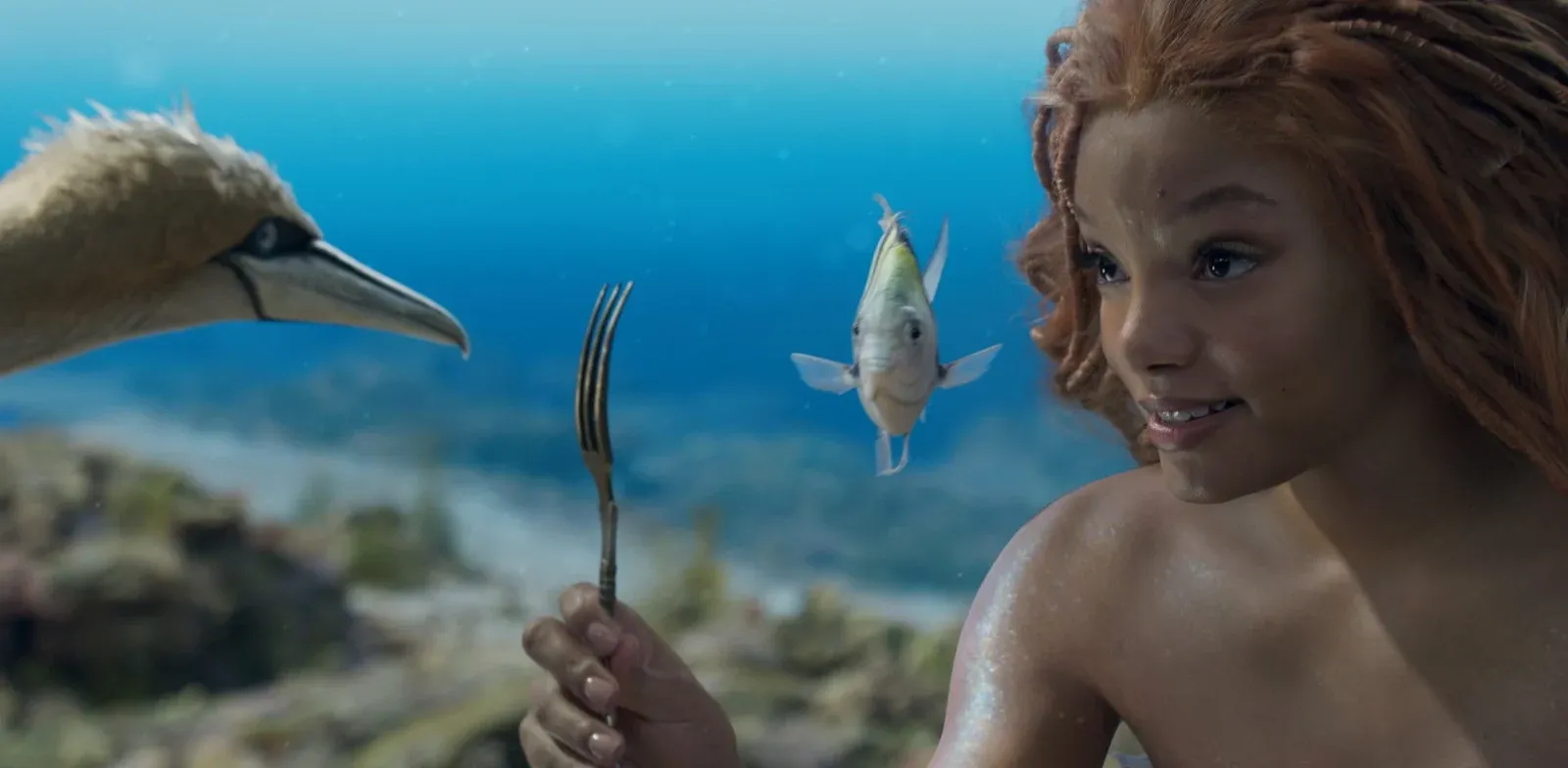 Une jeune fille rousse tient une fourchette sous l’eau face à un poisson et un fou de Bassan.