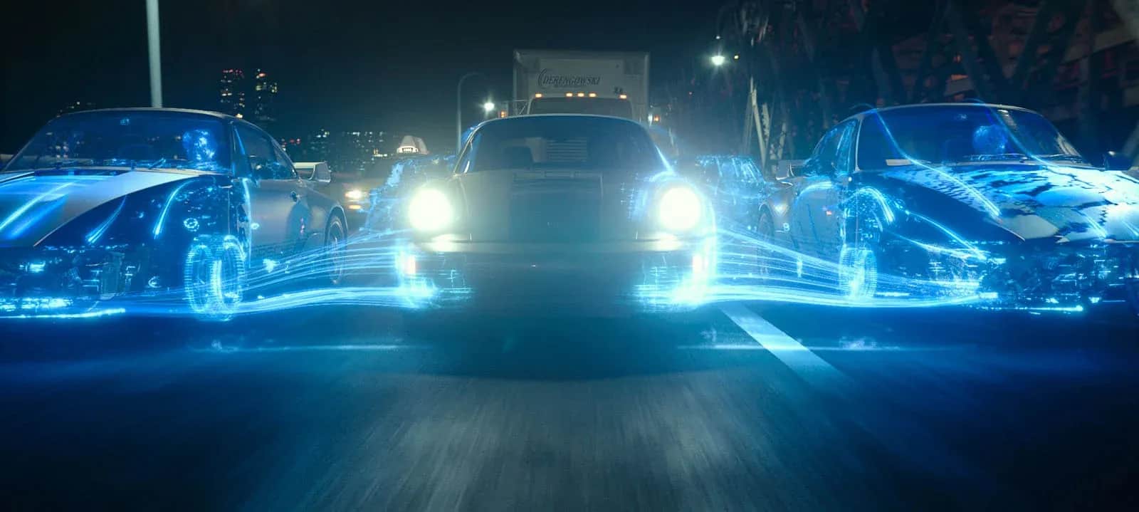 Trois voitures roulent de nuit en ville, entourées de traînées lumineuses bleues.