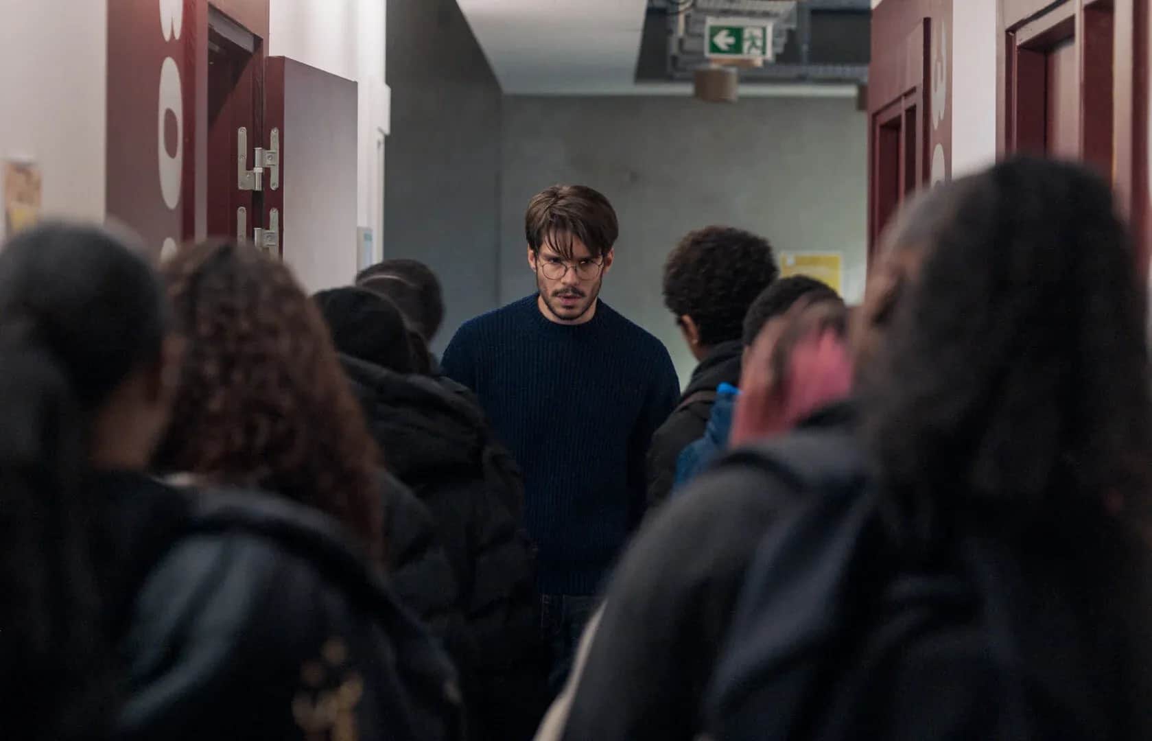 Un homme au centre d’un groupe de personnes dans le couloir d’un établissement scolaire