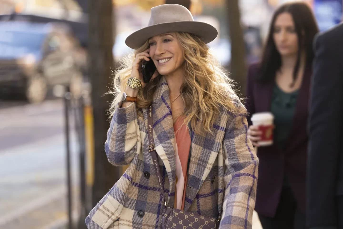 Femme souriante au chapeau, téléphonant dans une rue, avec des passants en arrière-plan