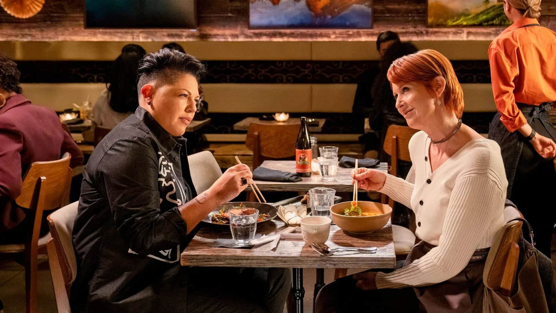 Deux femmes mangent avec des baguettes dans un restaurant asiatique.