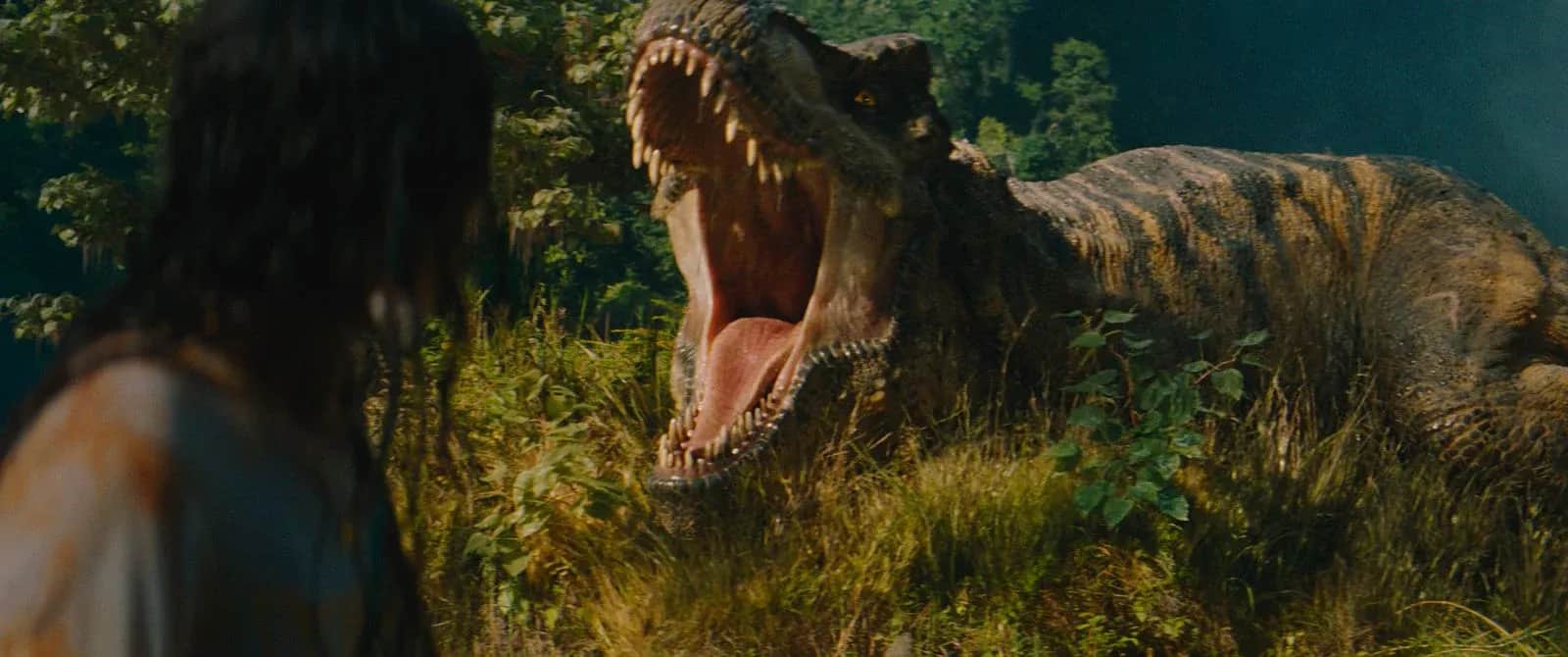 Une personne face à un dinosaure rugissant dans une végétation luxuriante