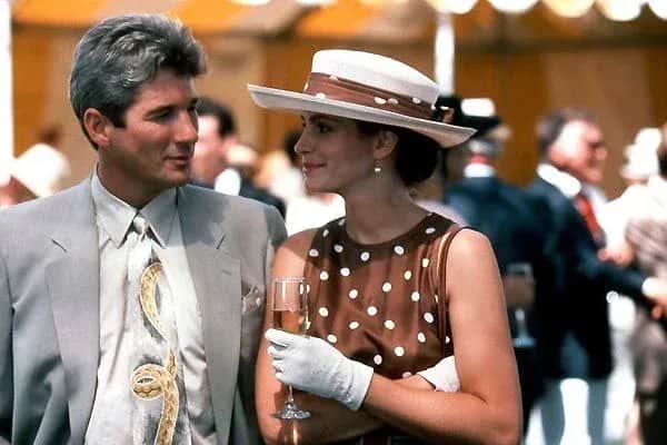 Un homme et une femme se regardent lors d’une réception en plein air, la femme tenant une coupe de champagne.