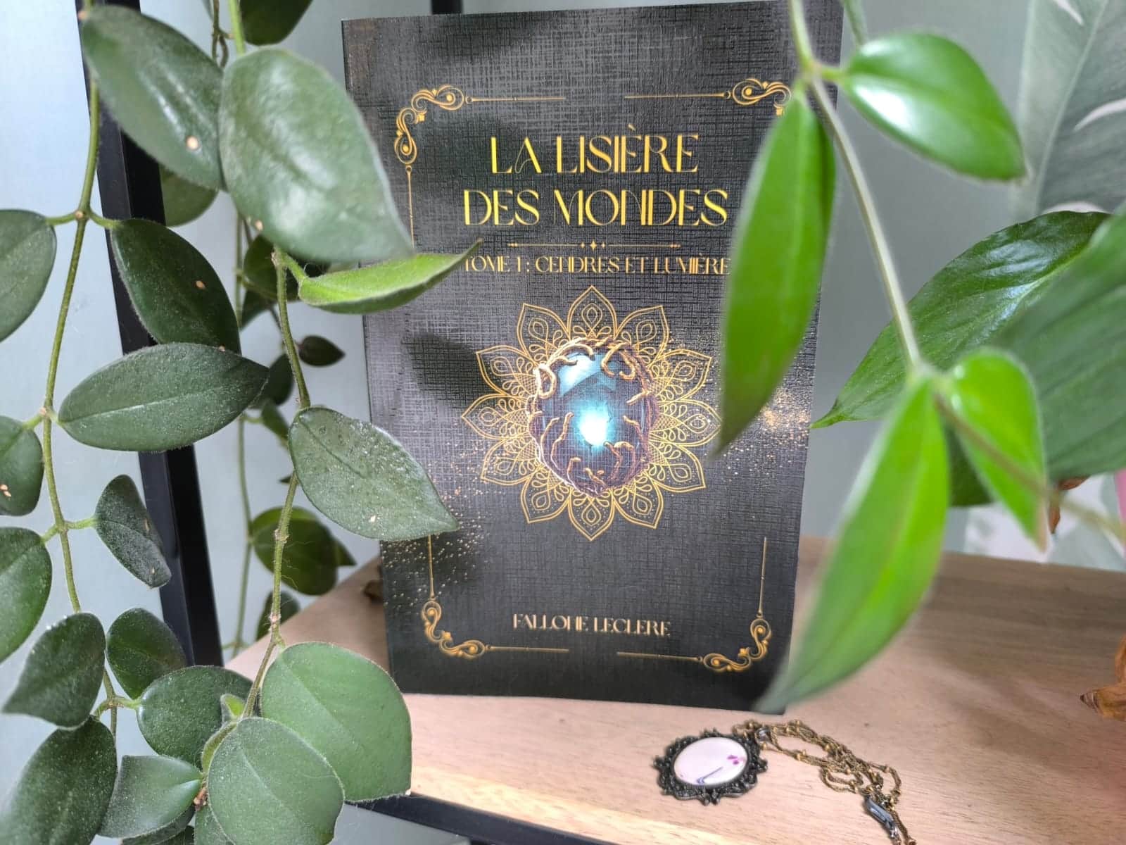 Jaquette de « LA LISIÈRE DES MONDES » avec un globe bleu lumineux entouré d’ornements dorés.