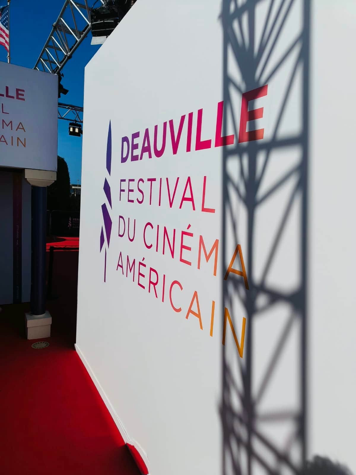 Festival du cinéma américain de Deauville affiché sur un panneau blanc, le long d’un tapis rouge.