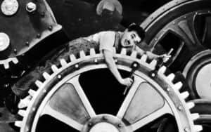 Un homme penché sur une grande roue dentée au milieu de mécanismes industriels.