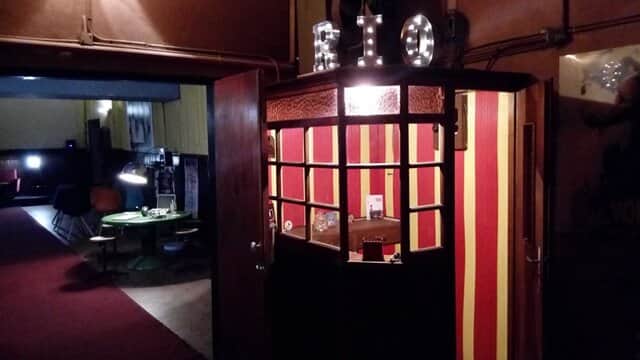 Entrée d’un cinéma avec enseigne lumineuse « BIO » et murs rayés rouge et jaune