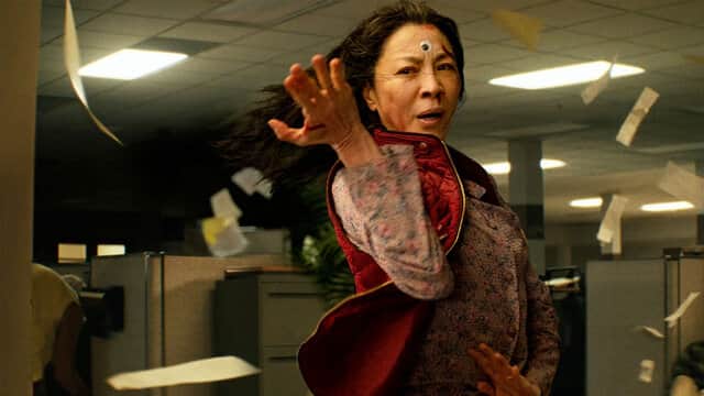 Une femme avec un troisième œil sur le front lance des papiers dans un bureau.