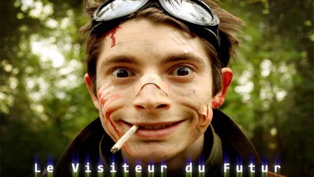 Affiche de « Le Visiteur du Futur » avec un homme au visage sale et des lunettes sur le front, tenant une cigarette.