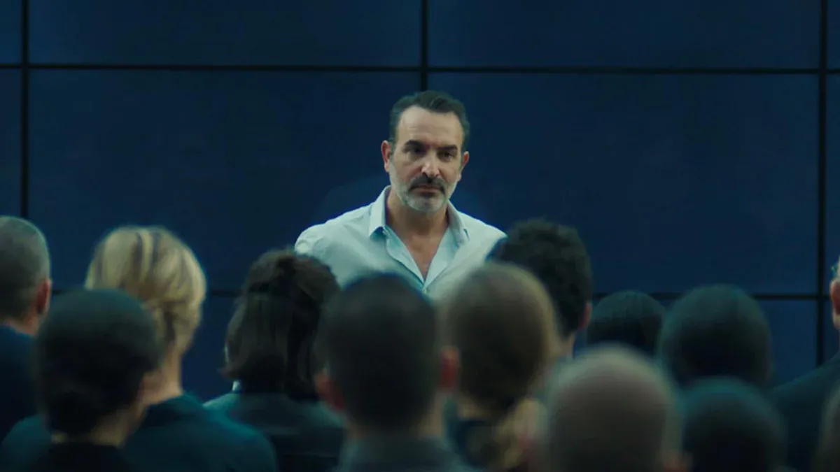 Un homme face à un groupe de personnes dans une salle sombre.