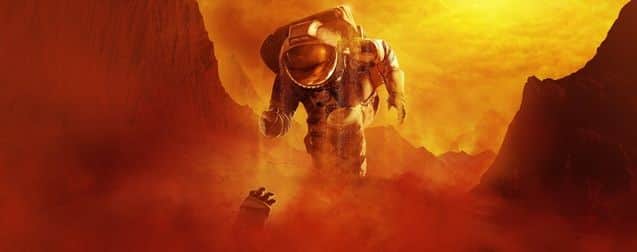 Un astronaute en combinaison flotte au-dessus d’un paysage rocheux embrasé par une lumière orange