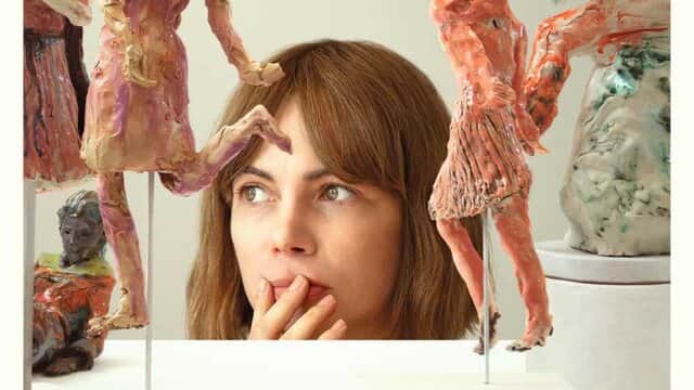 Une femme pensante entourée de sculptures colorées et abstraites.