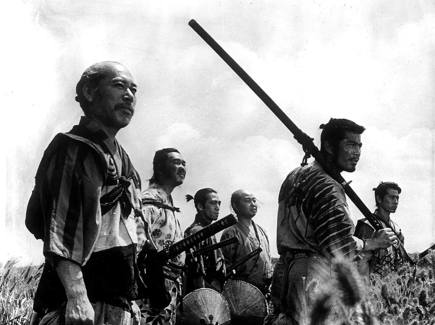 Un groupe de samouraïs armés de sabres, debout dans un champ sous un ciel nuageux