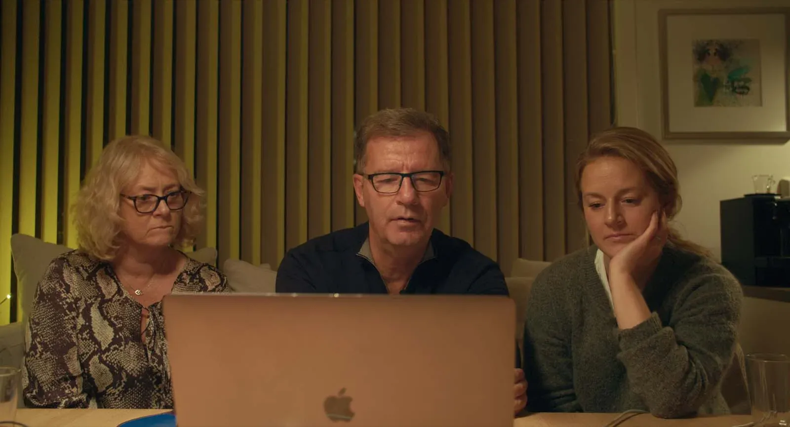 Trois personnes regardent un ordinateur portable dans un salon.