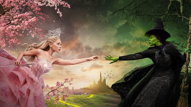 Deux femmes se tendant la main, l'une en robe rose et couronne, l'autre en robe noire et peau verte, avec un château au loin.