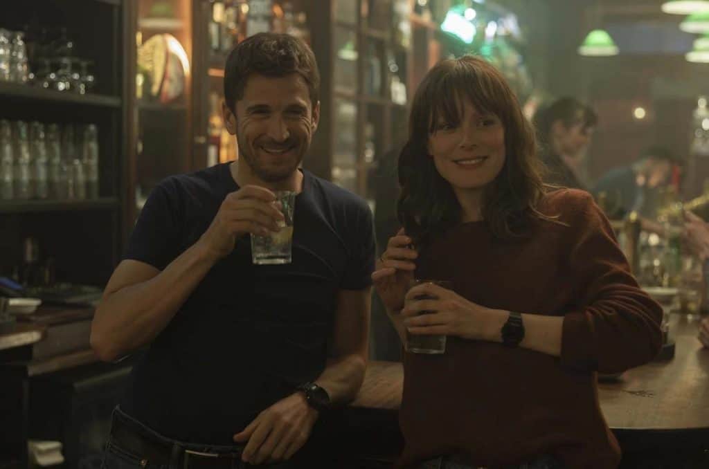 Un homme et une femme sourient en buvant dans un bar.