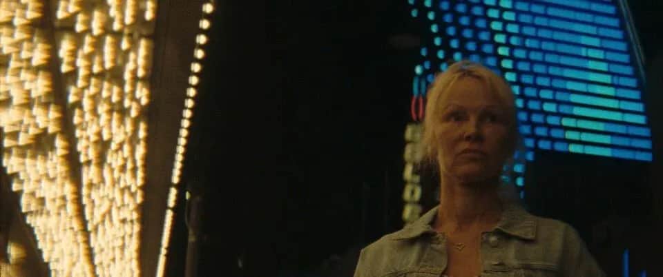 Une femme blonde devant des panneaux lumineux bleus et une installation éclairée en jaune