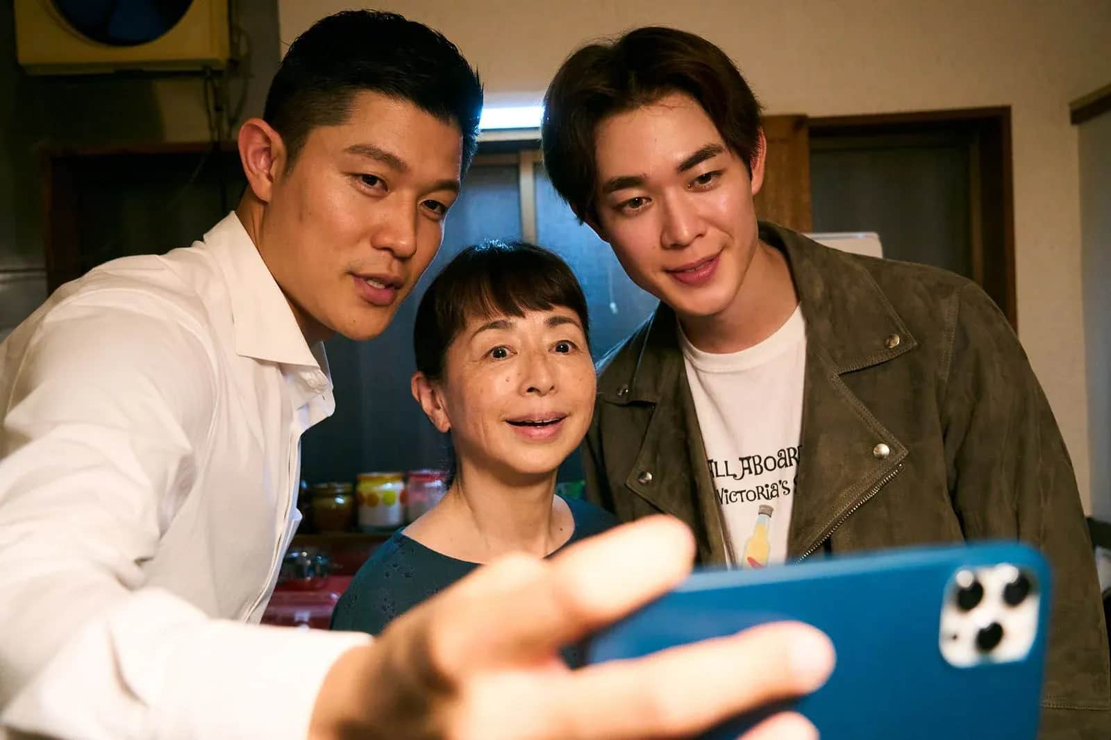 Trois personnes se prennent en photo avec un smartphone dans une pièce intérieure.