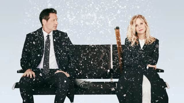 Un homme et une femme en manteaux noirs assis sur un banc sous la neige.